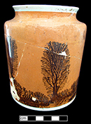 Creamware canister with mocha decoration on an orange slip.